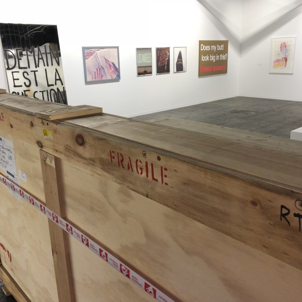 Harsch spécialiste transport d'œuvres d'art à artgenève. Une caisse fragile posée devant des tableaux.